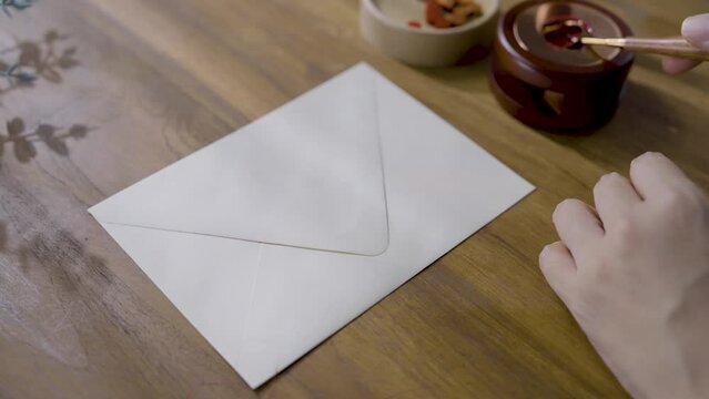Pressing a wax seal. Hands sealing a letter with hot red wax to seal or sign on envelope.