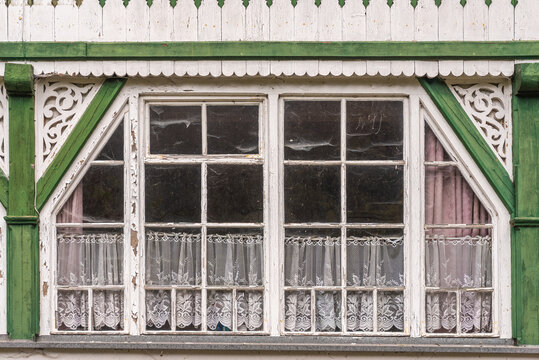 Altes verwittertes Holzkastenfenster mit Gardinen