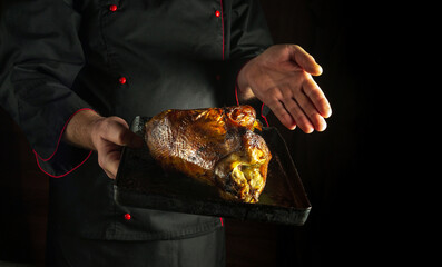 Baked chicken carcass on a baking sheet in the hands of a cook. The concept of preparing delicious...