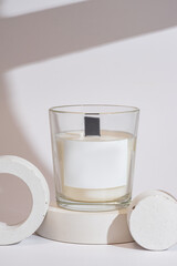 Handmade scented candles in a glass with on a podium. Soy wax candles with a wooden wick. Front view.