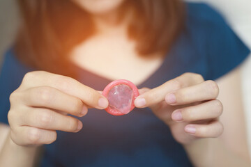 Condom ready to use in female hand, give safe sex concept on the bed Prevent infection and...