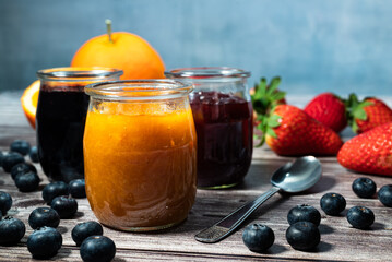 Homemade orange marmalade, assortment of homemade jams in glass jars. Front view, seasonal fruit...