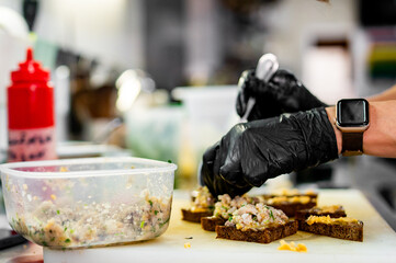 Professional chef cooking forshmak of herring with black bread in restaurant kitchen