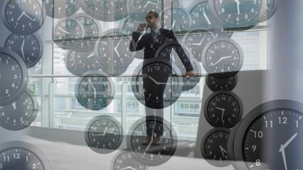 Animation of falling clocks with fast hands over caucasian businessman talking on smartphone