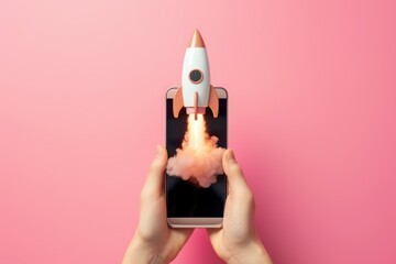 Obraz premium Hand holding cell phone and rocket taking off from the screen, startup, technology and business concept, pink background.