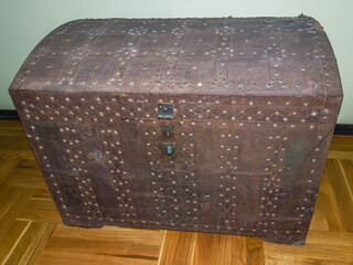 An antique antique chest for storing personal belongings, upholstered in iron. A large chest made of thick wood, upholstered with copper strips and wrought iron. A chest made in the 19th century.