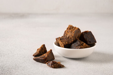 Kithul jaggery and treacle natural sweetener in white bowl on gray background. Copy space....