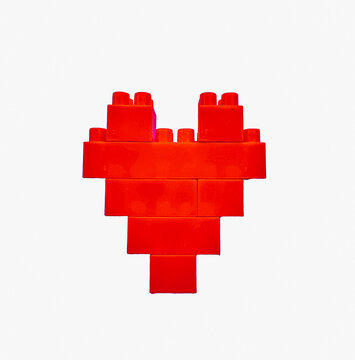 Red heart made of plastic  isolated on a white background. Photo of a red heart made from a children's construction set.