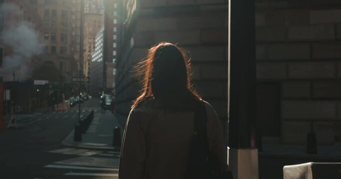 Brunette woman waiting at a zebra crossing and walking across busy New York City roads in bright sunlight.