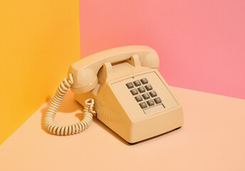 Beige vintage phone with gray buttons on the desk. Idea of communication.