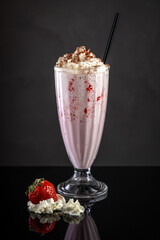 milkshake with strawberries in a glass on a black background