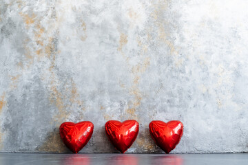 Three red hearts displayed on a table against a neutral backdrop