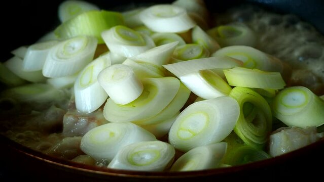 Frying Japanese spring onions with chopped fishes in pan, in door Chiangmai Thailand.