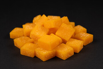 candied mango dices on dark background