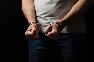 A criminal in handcuffs in front. Arrest for murder