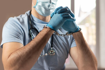 A medical officer, doctor, or quack in a blue medical uniform in handcuffs.