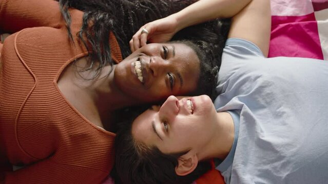 In the bedroom a couple of multi-ethnic girls hug and cuddle.
The two cute lesbian girls lying on the bed talking and having fun together.
Concept of diversity, love, and valentine's day