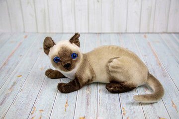 A Siamese cat made of papier-mache gray with beautiful brown paws and a muzzle on a wooden table. Pets Toys Recreation Hobbies.
