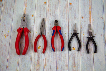 Pliers pliers round pliers lying in a row on a wooden table of gray color. Tools, construction, manufacturing, design, structures.