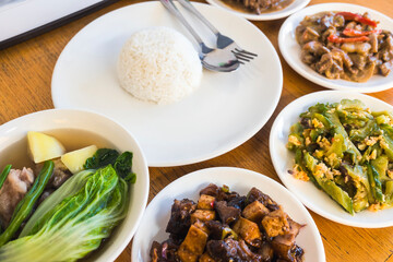 A table set with diverse Filipino dishes including rice, vegetables, and meat, ready for a family meal.