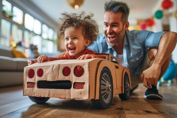 Father and son laugh and bond over a pretend cardboard car racing game
