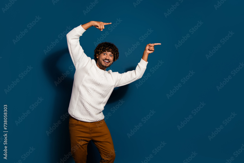 Wall mural photo of excited funky guy dressed white pullover pointing two fingers empty space isolated dark blu