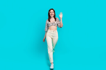 Full length photo of adorable excited lady dressed flower print top walking waving arm hi isolated turquoise color background