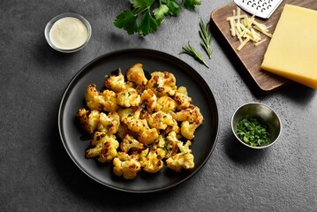 Roasted cauliflower on black plate over dark stone background