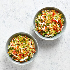 Crunchy thai style chicken salad in bowls over light stone background