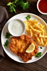 Homemade breaded wiener schnitzel served with potato fries and sauce o