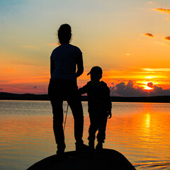 a girl fishes on the lake against the backdrop of a beautiful sunset to feed her family