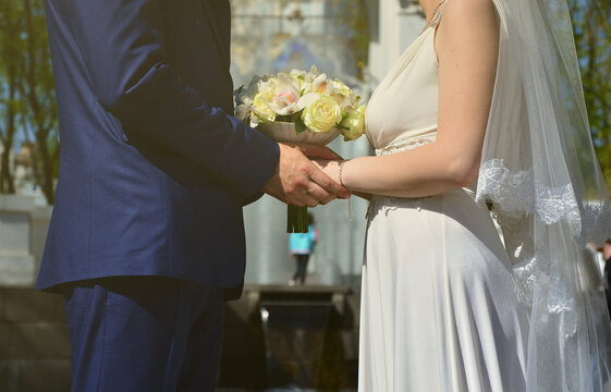 The newlywed couple is holding a beautiful wedding bouquet. Classical wedding photography, symbolizing unity, love and the creation of a new family