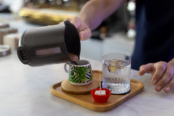 The male hand is pouring coffee in cup of coffee