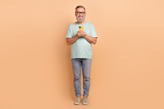 Full length photo of handsome man hold use apple iphone gadget instagram tiktok isolated on beige color background