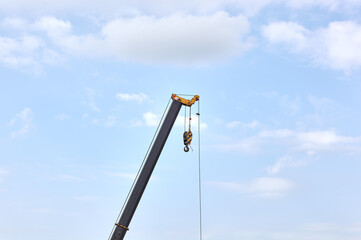 Detail from a floading cargo crane over blue sky background. Boom crane part of mobile crane using to heavy lifting and move object in many industry such as construction, transportation, erection etc