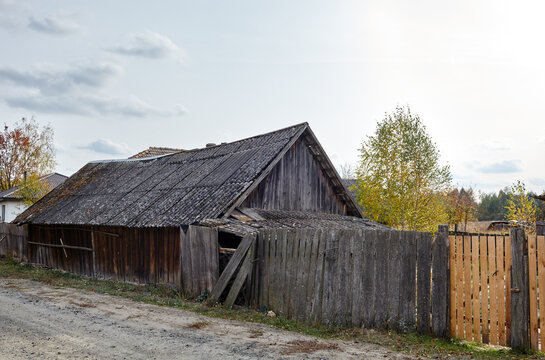 Old barn with wooden fence in countryside. Road in the village, summer rural landscape