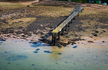 Fototapeta na wymiar Small pier at low tide on the beach with seaweed in summer