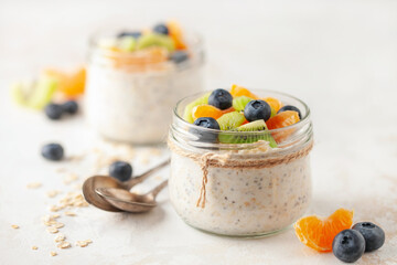 Healthy diet breakfast. Overnight oatmeal with chia seeds and fruits in a glass jar on a wooden background.