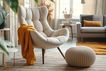 Comfy beige armchair and ottoman on a warm rug in modern lounge with charcoal couch and antique decor.
