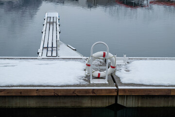 Snow-Covered Dock With Lifebuoy and Wooden Pier on a Serene Winter Morning