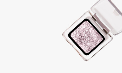 Bright light glitter, highlighter, eye shadow. In transparent packaging on a light background