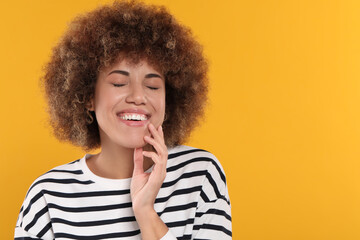 Fototapeta na wymiar Woman with clean teeth smiling on yellow background, space for text