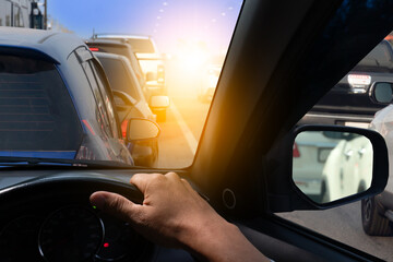 Hand of man driving car stop in traffic light, Single hand on steering wheel, Go to business trip or travel in city. Many cars on the front. with blue sky. - obrazy, fototapety, plakaty