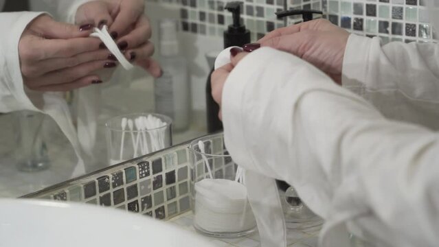 Closeup of a woman taking out a cotton pad from a jar for facial cleansing, makeup and skin care in the bathroom