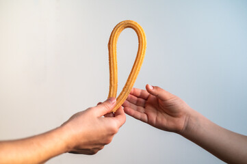 hand of an adult giving a churro to a child, full of fat and oil, typical Spanish