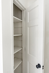 Interior white solid wood closet or kitchen pantry with wood shelves in an older house that has been newly renovated and painted