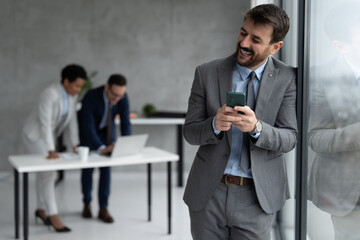 Smiling businessman using phone and texting