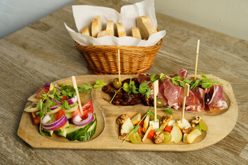 Selection of prosciutto, local cheese, chorizo sausage and vegetables on a wooden plate