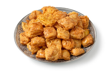 Plate with homemade Moroccan deep fried, square shaped, Rghayef honey cookies isolated on white background close up