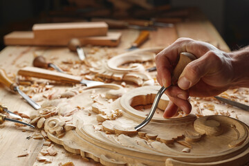 Carpenter working on wooden furniture with hand carving. Wood carving art with hand tools Close-up...